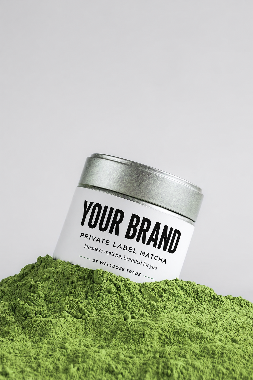 Private label matcha tin branded with your own logo, on a bed of green matcha powder
